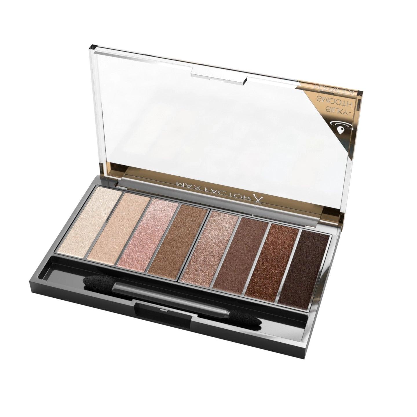 An open eyeshadow palette with eight shades ranging from light beige to dark brown, featuring a dual-ended applicator.